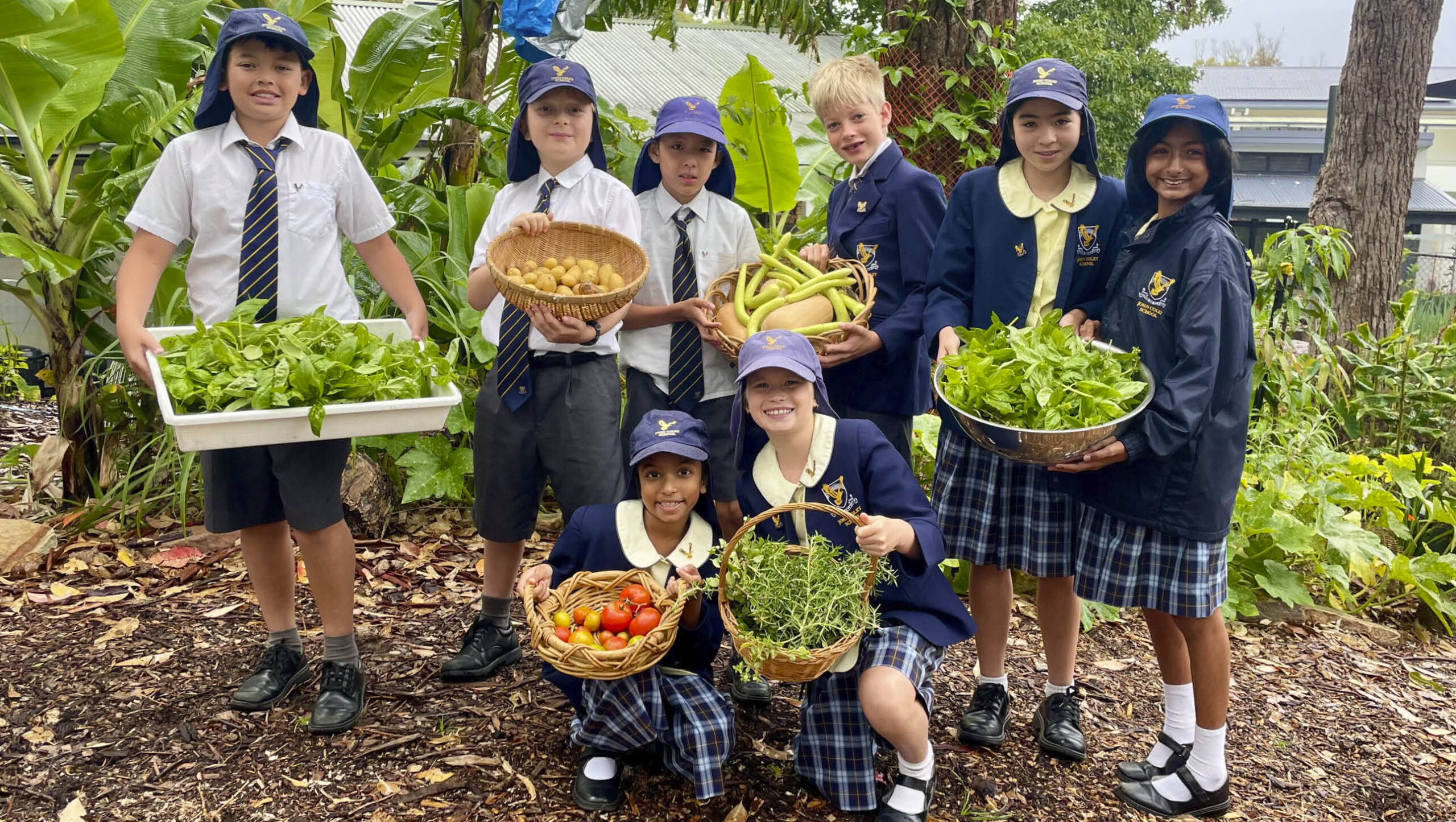 Students at John Colet primary school showing off vegies grown in their garden.