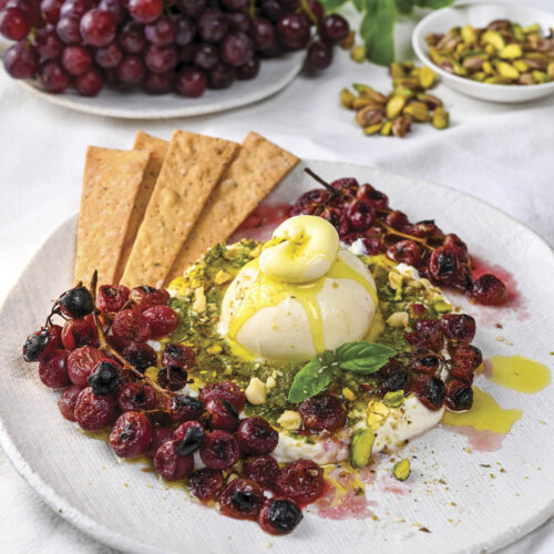 Mediterranean burrata with baked grapes and crackers for dipping.