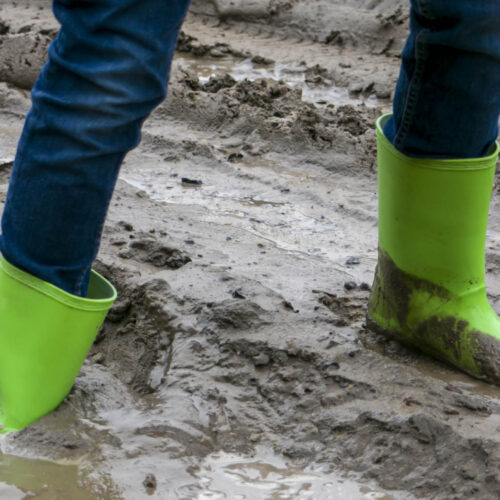 Person in green gumboots stuck in mud.