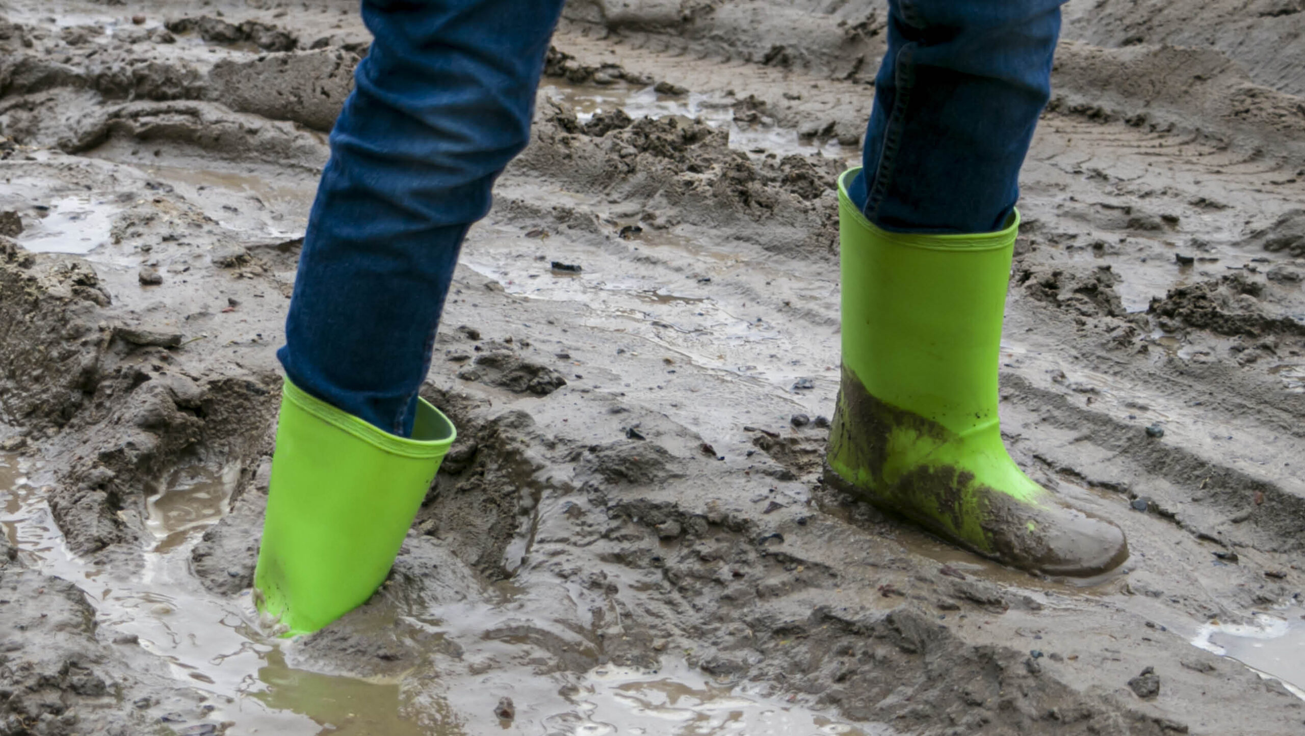 Person in green gumboots stuck in mud.