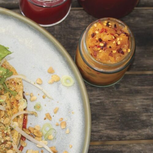 A jar of yellow nectarine kimchi beside a plated salad