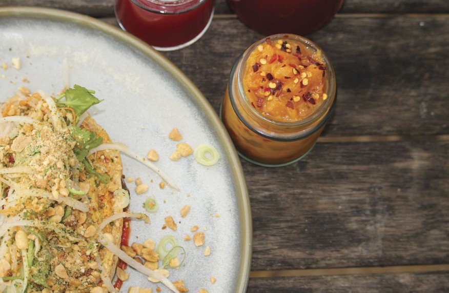 A jar of yellow nectarine kimchi beside a plated salad