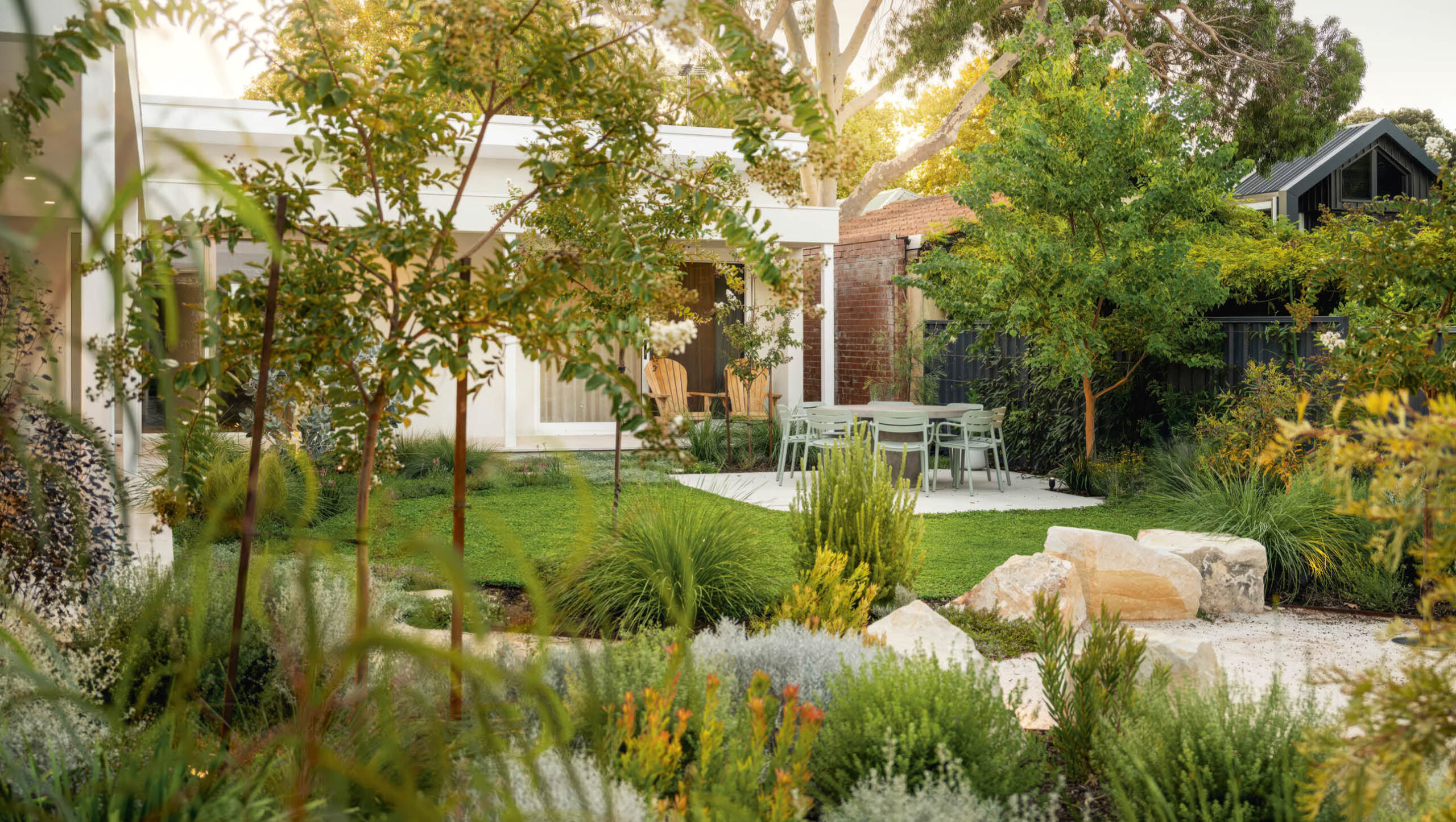 An Australian backyard with a lush lawn in the centre, surrounded by native trees and bushes.